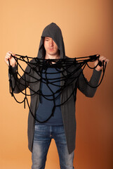 A man in a gray hood entangled in a web. The concept of social problems that drag into the web for Halloween