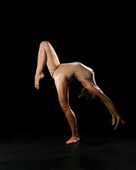 Fototapeta na wymiar A gymnast performs exercises in a flesh-colored swimsuit for flexibility on a uniform background