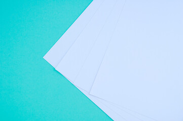 Four white sheets of paper  turquoise background. Stationery.