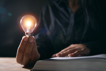 woman holding a light bulb of a book