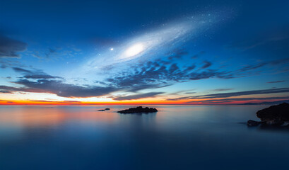 Fototapeta na wymiar Andromeda Galaxy over the sea with sunset reflection on the sea 