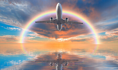 Fototapeta na wymiar Airplane flying over tropical sea with amazing rainbow at sunset