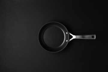 Empty black frying pan on black wooden table background