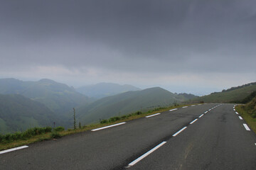 Une  route de montagne serpente au sommet des Pyrénées, surplombant une vallée verdoyante.