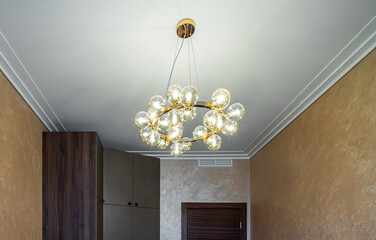 Modern designed chandelier with burning lamps. Contemporary interior.