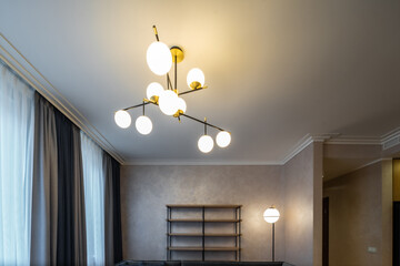 Stylish chandelier with round lamps on ceiling. Modern design.