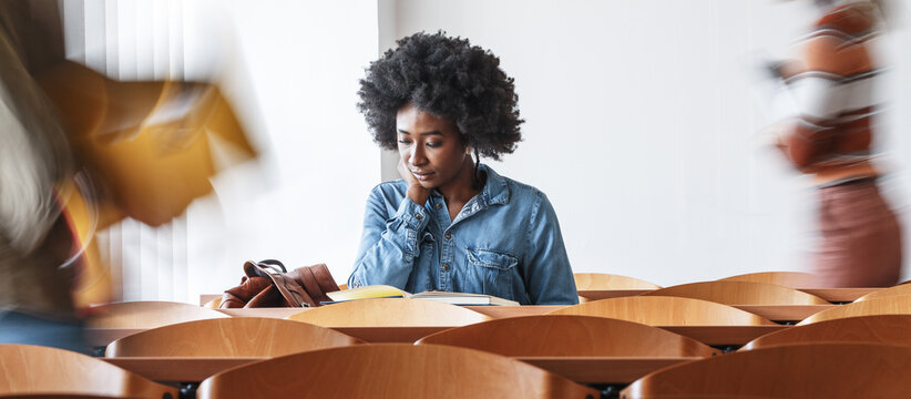 Young black female student taking a test in university classroom.	
