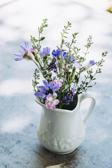 Bouquet de fleurs des champs dans un vase blanc avec un fond gris
