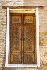 Antique wooden street door, expertly carved with traditional patterns and inscriptions from  Quran. Mausoleum of Bibi-Khanym in Samarkand, Uzbekistan