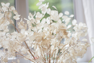 artificial ornamental plant with leaves made of white mother of pearl. in a vase in front of the...