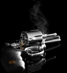 Chrome revolver with tilted drum after firing single bullet. Russian roulette concept.