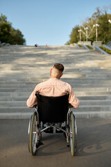 Man in wheelchair at the stairs, back view