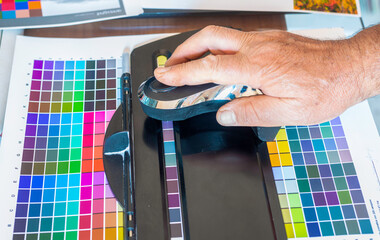 Technician uses a spectrocolorimeter to read patches with various colors for color management...
