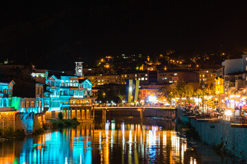 Fototapeta na wymiar トルコ　夜になってライトアップされたアマスィヤに流れるイェシル川と旧市街の街並みと時計塔