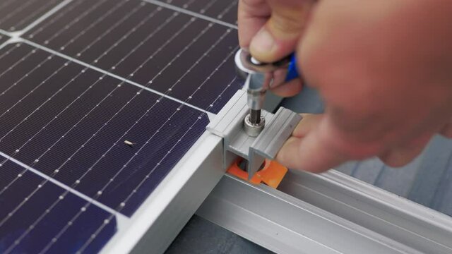 Close up of worker installing and working on maintenance of photovoltaic panel system installed. Mounting solar panel, installing solar panels on the roof of the house. Connection of solar panels.