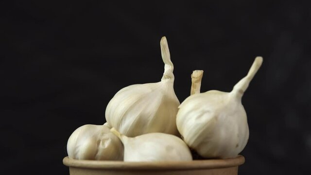 Heap of garlic spinning on black background, close shot of an heap of garlic solwly rotating on a black background