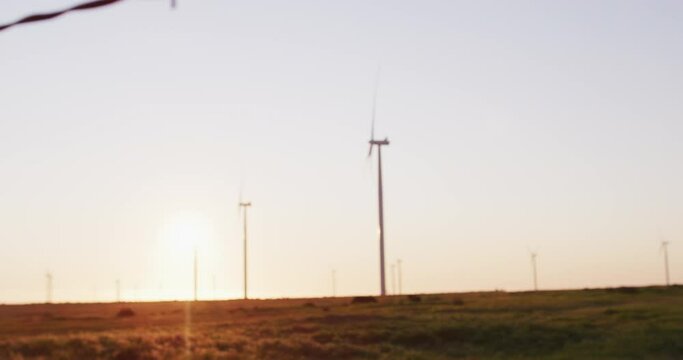 Wind turbines in countryside landscape with cloudless sky at sunset