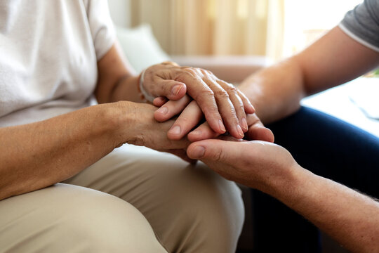 Cropped Shot Of An Unrecognizable Male Nurse Holding His Senior Patient's Hand In Comfort. Mother And Son Hands Holding Together In Love And Support After Losing Loved Ones Amid Coronavirus Outbreak.