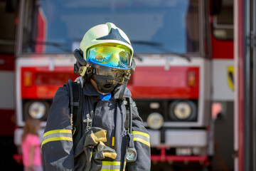 Child, cute boy, dressed in fire fighers cloths in a fire station with fire truck