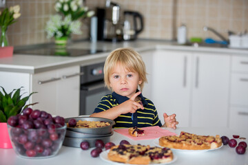 Cute little toddler child, eating homemade plum pie at home