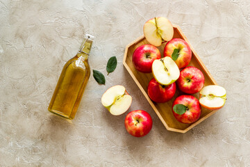 Apple cider vinegar in glass bottle with fresh red apples