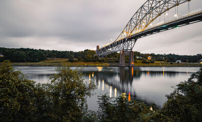 Tranquil seascape over the Cape Cod Canal with lighted Sagamore Bridge at dawn