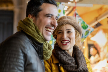 Portrait of mature woman and a man laughing outdoors at the Christmas market.