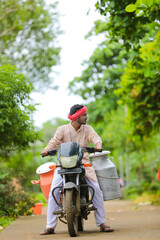 Rural scene : Indian milkman distribute milk on bike