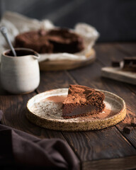 Chocolate cake on a wooden table. A piece of brownie on a brown background. Cocoa and chocolate pieces. Serving dessert.