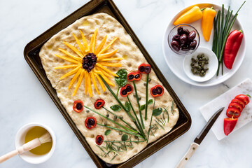 Top down view of a homemade artistic focaccia bread using vegetables pieces for the picture.