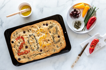 Top down view of a focaccia bread topped with various vegetables forming the numbers 2022. New year...