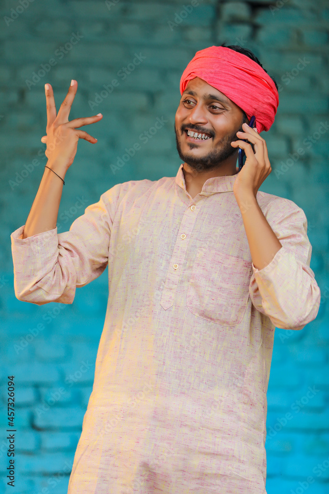 Wall mural Indian farmer talking on smartphone at home.