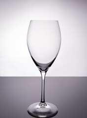Empty transparent wine glass on white and gray background