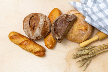 bread and wheat on the table, loaves of assorted freshly baked bread on a stone background