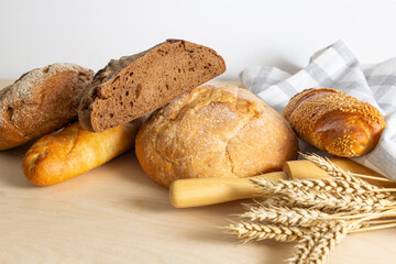 assortment of bread, bread and wheat on the table, loaves of assorted freshly baked bread on a stone background
