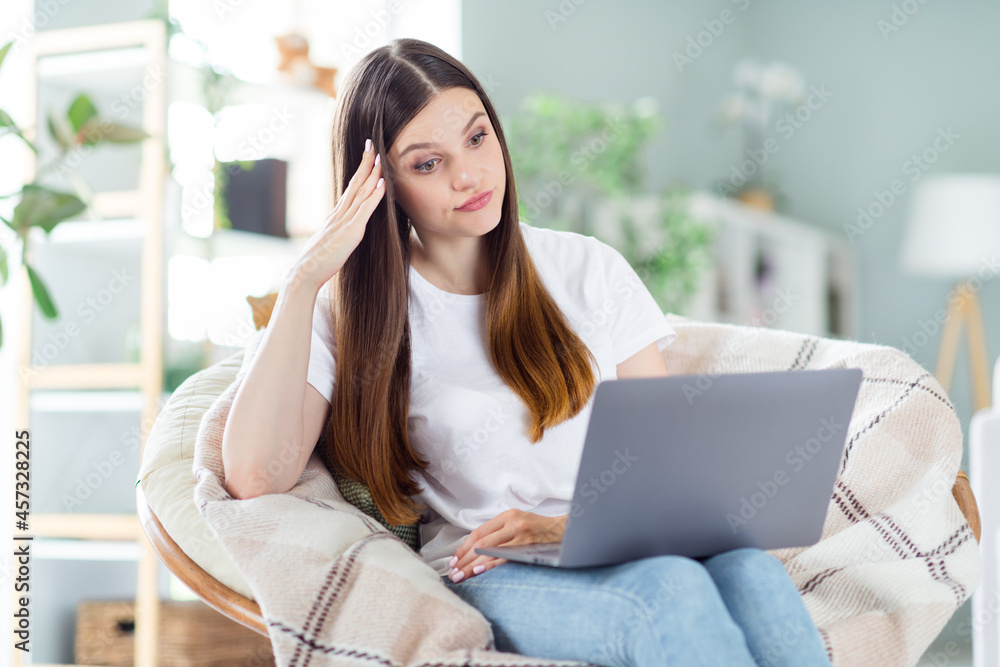 Sticker Portrait of attractive frustrated girl sitting in chair using laptop watching boring video at home light living room indoors