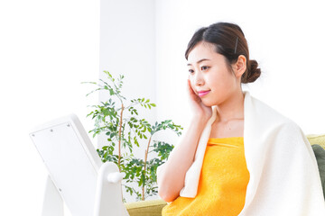部屋でスキンケアをする若い女性