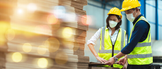 Asian male and female engineers wear protective gear and masks. Check the orderliness of the work within the warehouse.