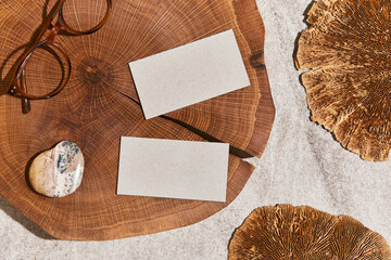 Fototapeta na wymiar Flat lay of stylish composition with mock up visit cards, rock, wood, natural materials, dry plants and personal accessories. Neutral colors, top view, template.
