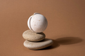Vanilla aroma bath bomb in spa composition with dry flowers and stone on brown background....