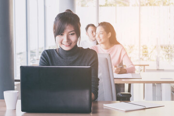 Asian business woman who sitting work by notebook in feeling happy at the office with daylight from window and blur garden background.