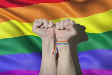 Gay guy's hands fist and LGTB flag and bracelet