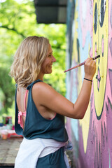 Side view of female artist painting wall