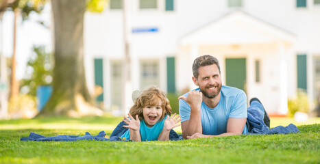 happy father with kid relax together on green park grass, copy space, family day