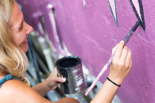 Smiling artist painting wall mural