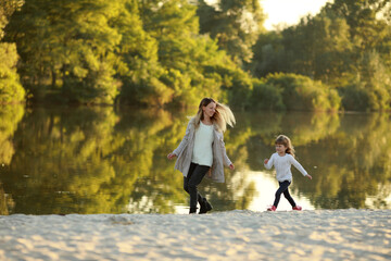 Fototapeta premium Mother and daughter run on beach near river.