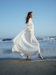 Fototapeta na wymiar pretty woman in white dress by the ocean posing vacation