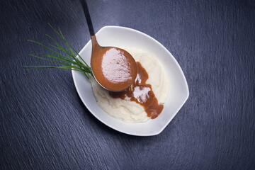 Mashed potatoes with gravy on blackstone background. Dark food