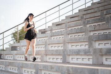 A healthy adult Asian woman running up on concrete stairs of the city stadium to strengthen body