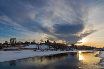 Sunset on the background of the old city of the frozen river.